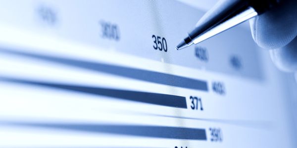 Close-up of a pen pointing at a bar chart with numerical values.