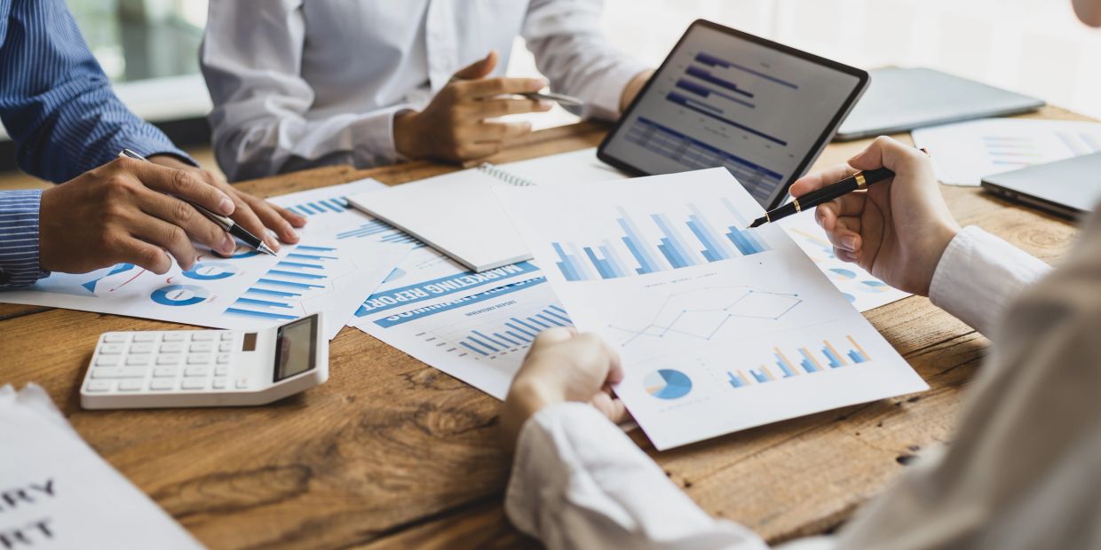 People analyzing financial data and graphs around a table.