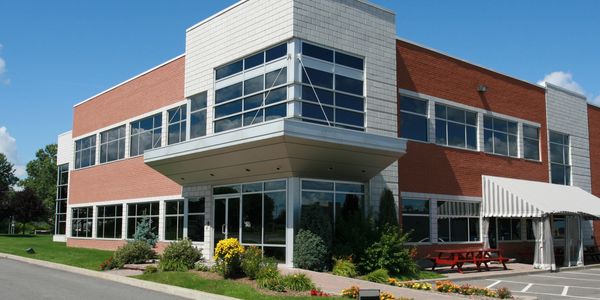 Modern two-story office building with large windows and landscaping.