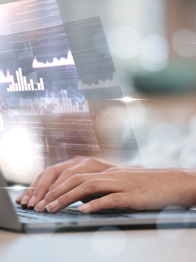 Hands typing on a laptop with digital financial charts overlay.