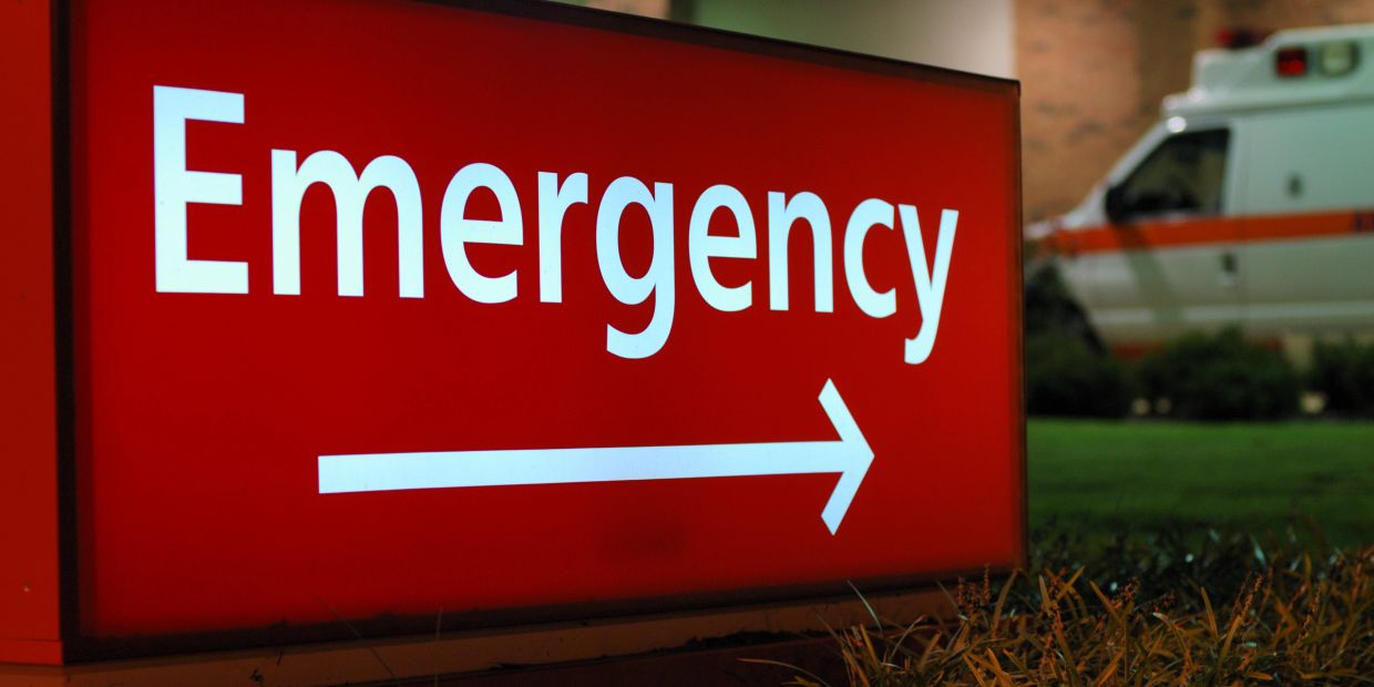 Red emergency sign with an ambulance in the background.