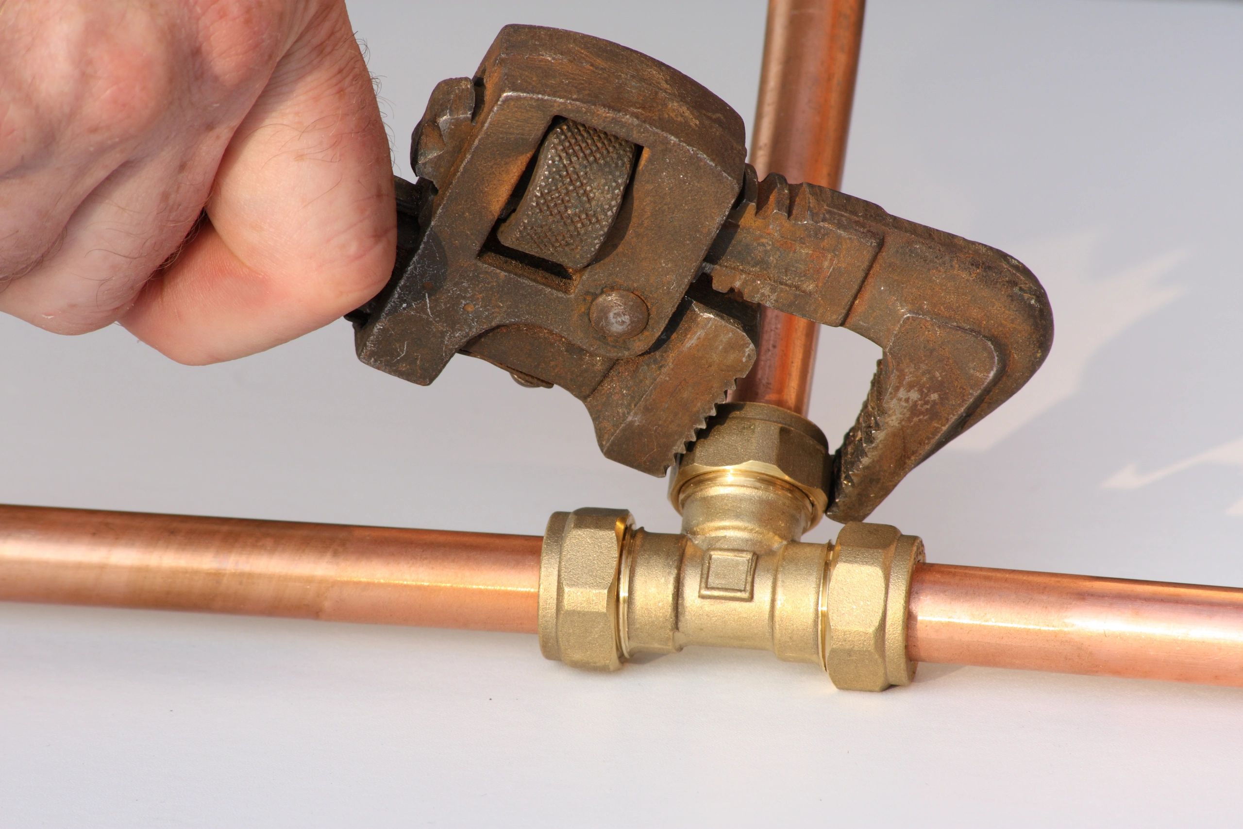 Plumbing tools and copper fittings on a house blueprint.
