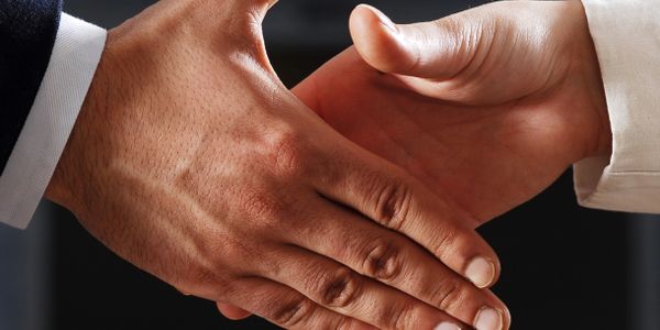 Two people shaking hands in a business setting.