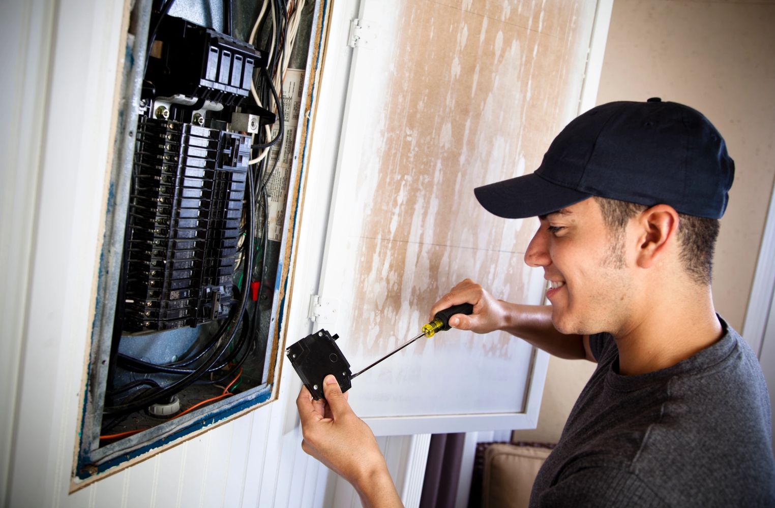 Electrician fixing a circuit breaker inside an electrical panel.