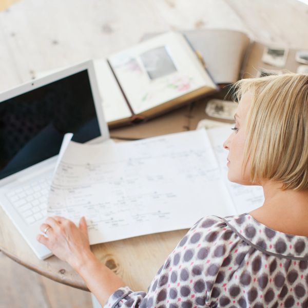 Woman studying genealogy charts with a laptop and family albums.