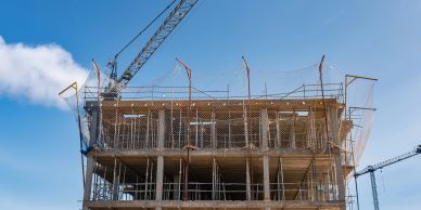 Building under construction with cranes and scaffolding.