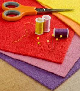 Colorful sewing materials including scissors, threads, pins, and felt sheets.