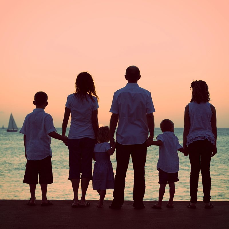 Family watching the sun setting over the ocean.