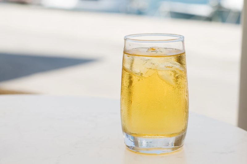 Glass of apple juice with ice on a restaurants table.