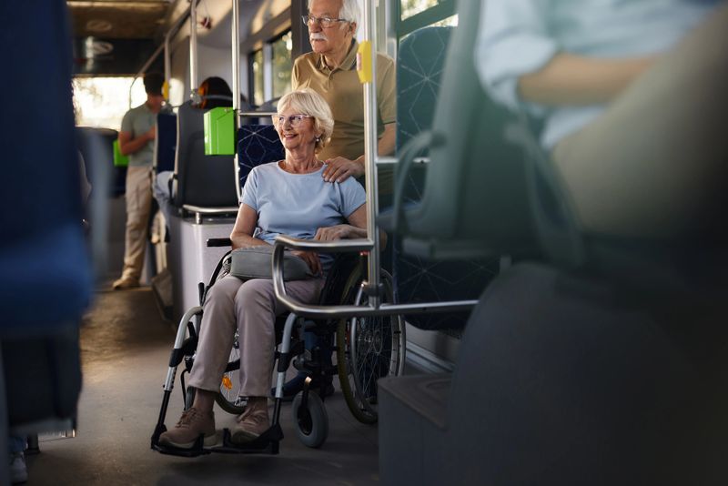 Happy disabled senior woman in a wheelchair and her husband traveling by a bus.