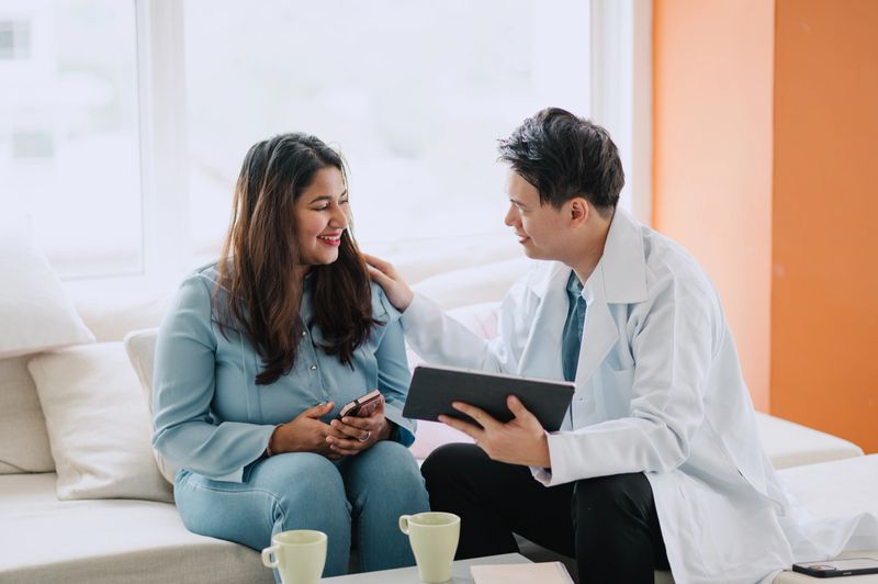 Asian Chinese male doctor explaining to his Asian Indian patient with digital tablet.