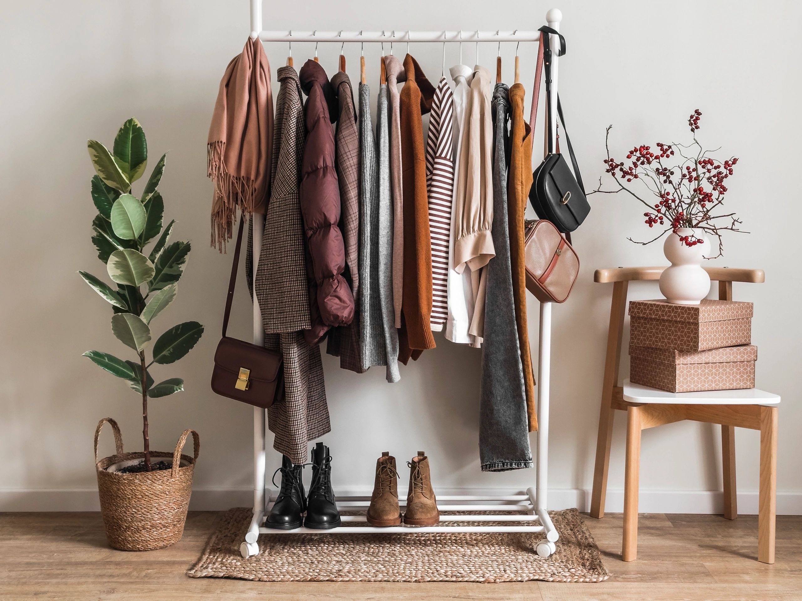 Cozy fall wardrobe with earth tones, boots, and accessories in a stylish room.