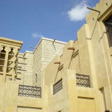 Traditional Middle Eastern architecture with wind towers under a clear blue sky.
