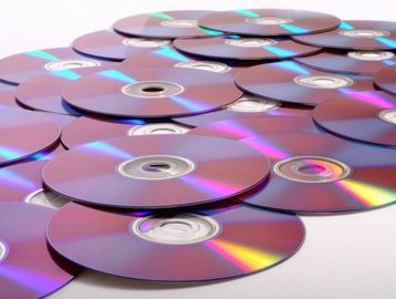 A pile of shiny recordable DVD discs scattered on a white surface.