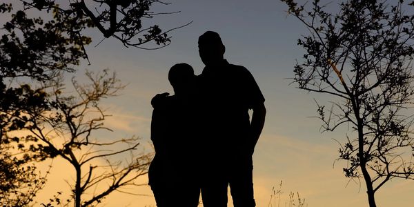 Silhouette of two people against a sunset sky.