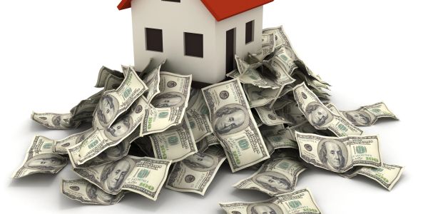 A small house model surrounded by piles of dollar bills.