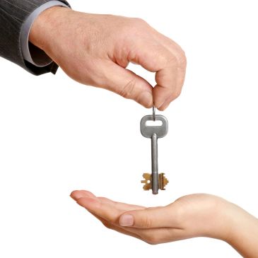 Hand giving a vintage key to another hand.