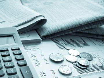 Calculator, coins, and newspapers on financial charts and documents.