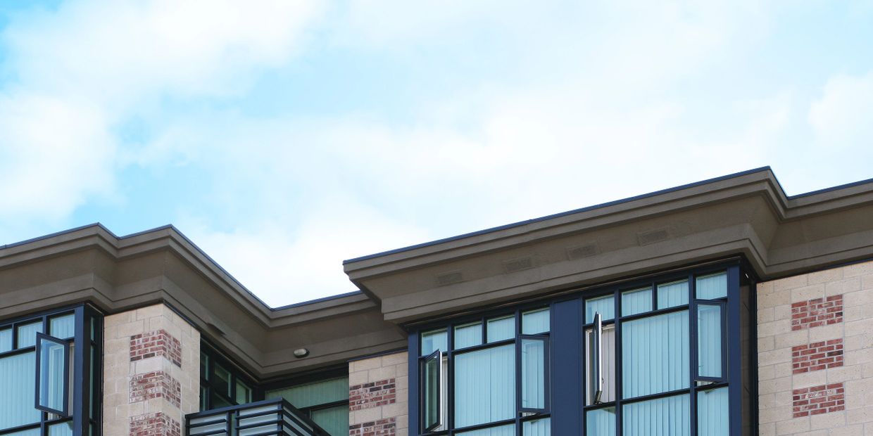 Modern apartment building with large windows and blue sky.