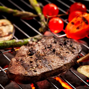 Grilled steak with pepper and vegetables on a barbecue grill.