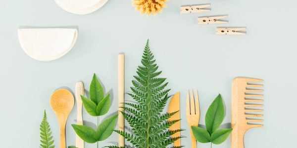 Eco-friendly bamboo utensils and green leaves arranged on a light background.