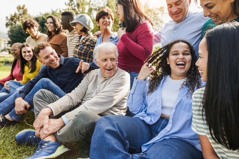 Group of multigenerational people having fun together - Multiracial friends of different ages smiling outdoor - Main focus on african curvy girl face