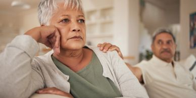 Elderly woman looking thoughtful with man comforting her.