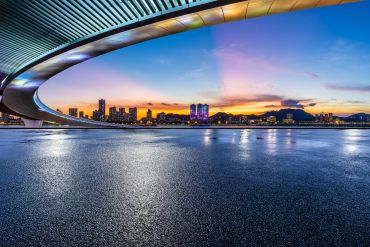 City skyline at sunset with a curved bridge.