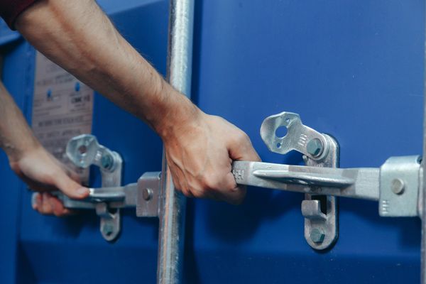 Hands locking a blue shipping container.