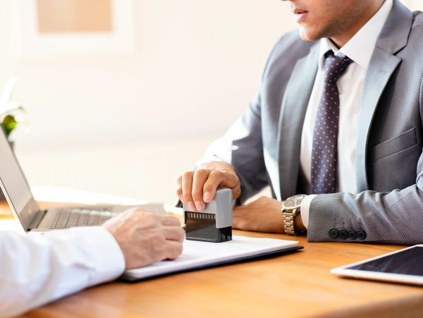 Smiling professional woman holding documents and pen at office desk.
