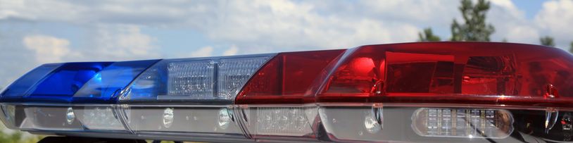 Close-up of a police car's red and blue emergency lights against a cloudy sky.