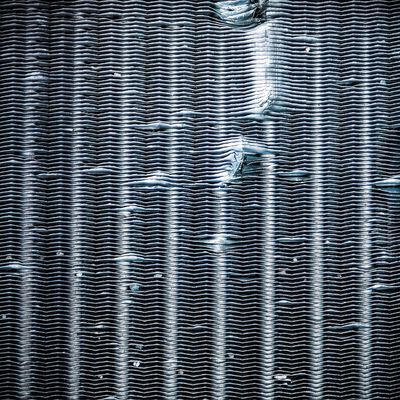 Close-up of a textured, corrugated metal surface with light and shadow patterns.