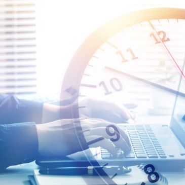 Person typing on a laptop with a clock overlay.