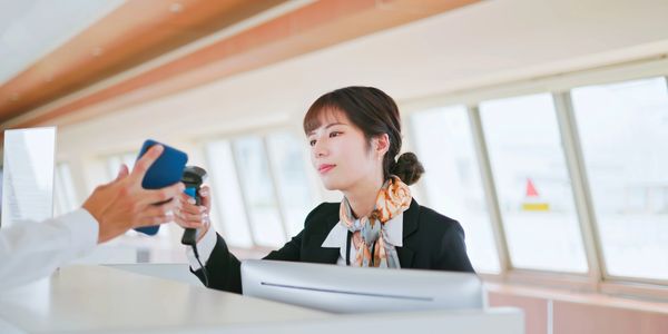 Airport staff scanning a passenger's mobile phone for boarding.