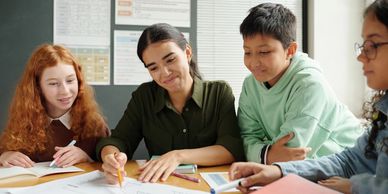 Teacher helping students with a group study session in a classroom.