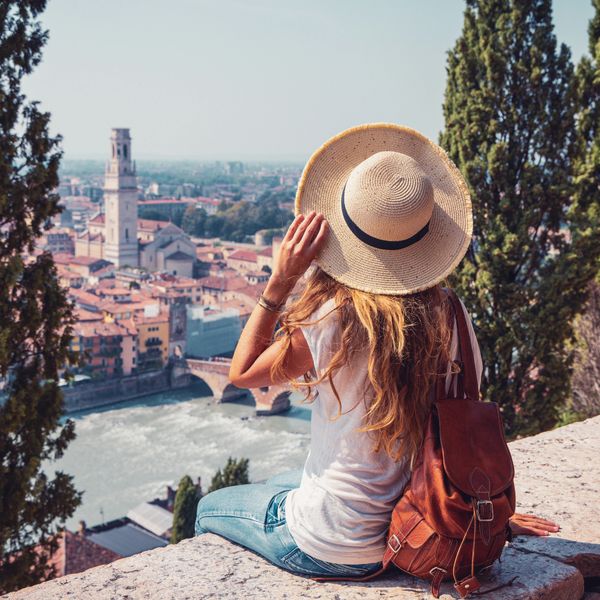 Woman with a hat overlooking a scenic city and river.