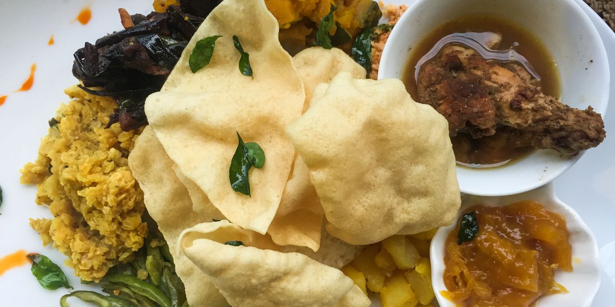 A plate of Indian food with papad, curry, and vegetables.
