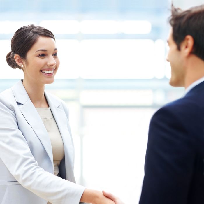Two professionals shaking hands in a bright office setting.