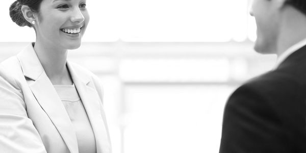 Two professionals shaking hands in a bright office setting.