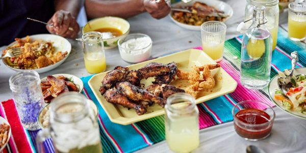 A colorful meal with fried chicken and drinks on a bright tablecloth.