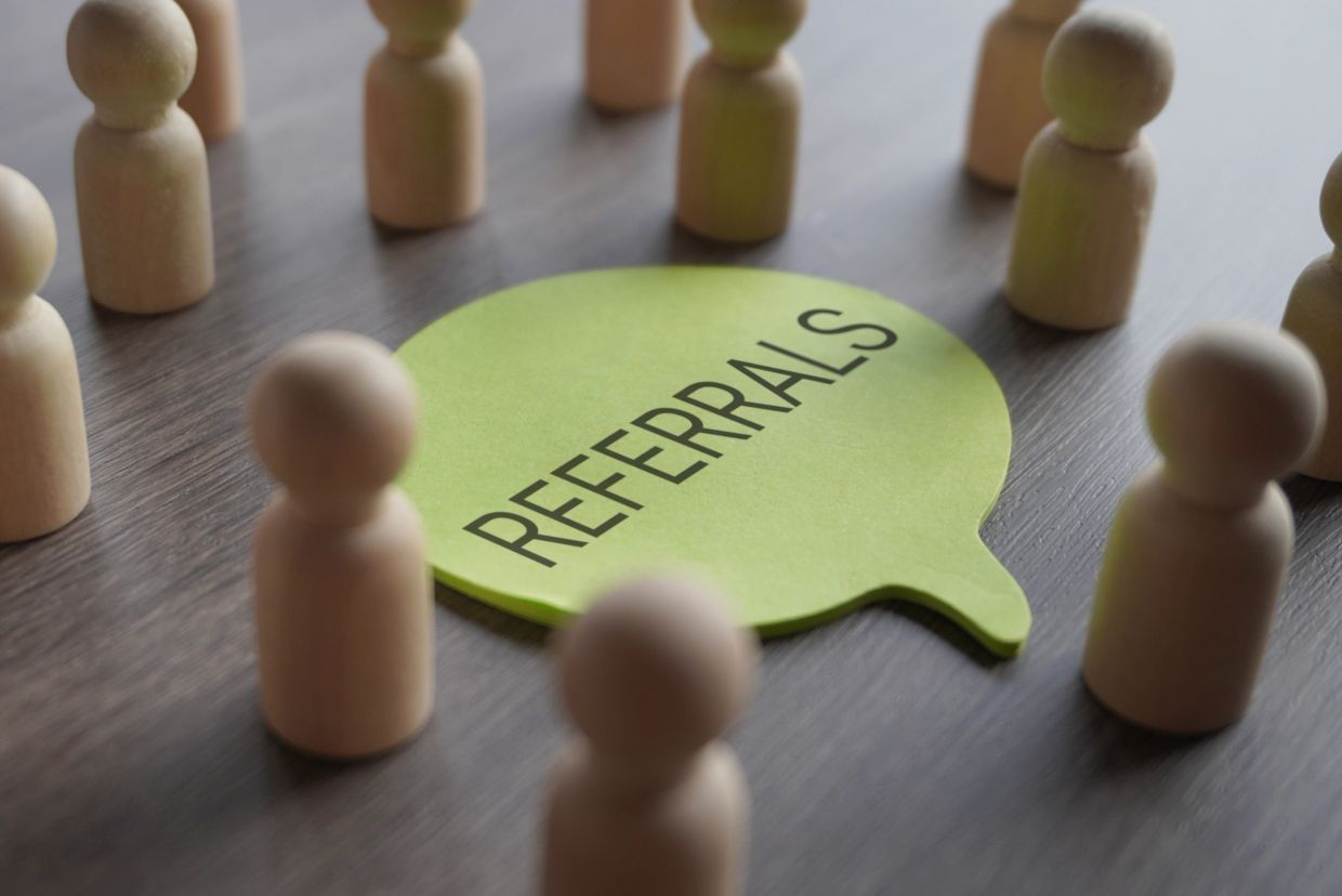 Wooden figures surround a green note labeled 'Referrals'.