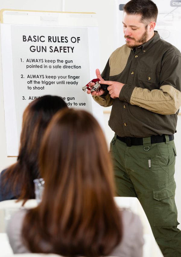 Instructor teaching gun safety rules using a revolver in front of a class.