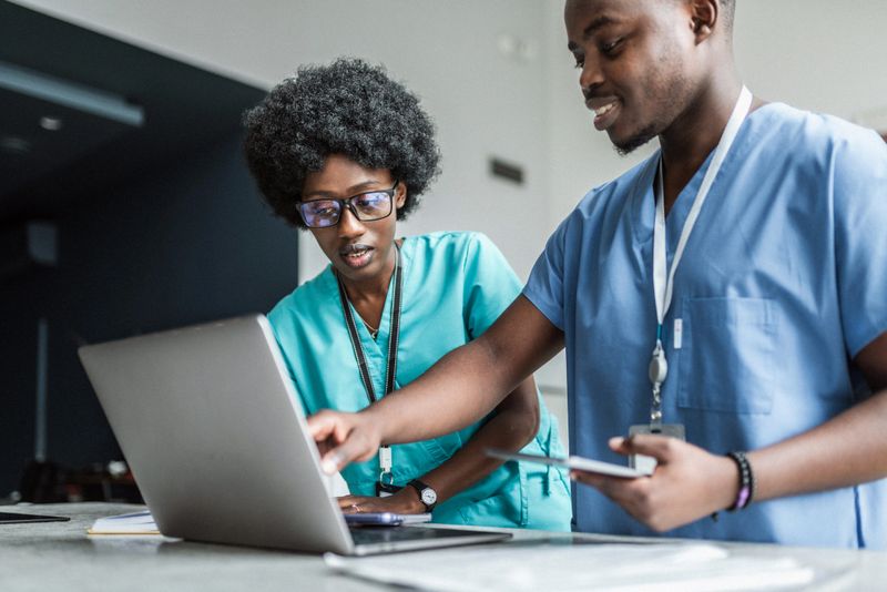 Two medical workers at work using laptop and discussing