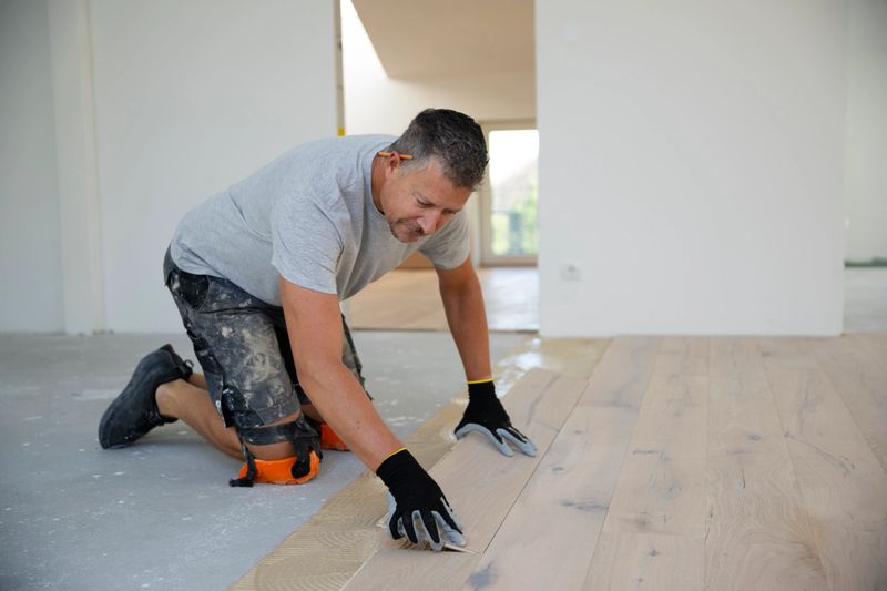 middle-aged man with gray hair glued, laying parquet floor in my loft apartment, top floor