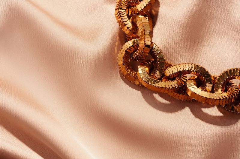 Golden chain necklace on silk background close up photo