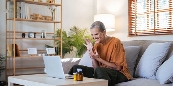Elderly woman happily video chatting on a laptop in a cozy living room.
