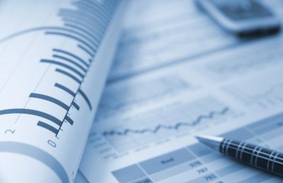 Financial graphs and pen on paper documents.