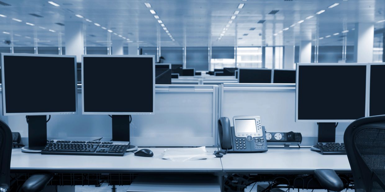 Empty modern office workspace with multiple computers and telephones.