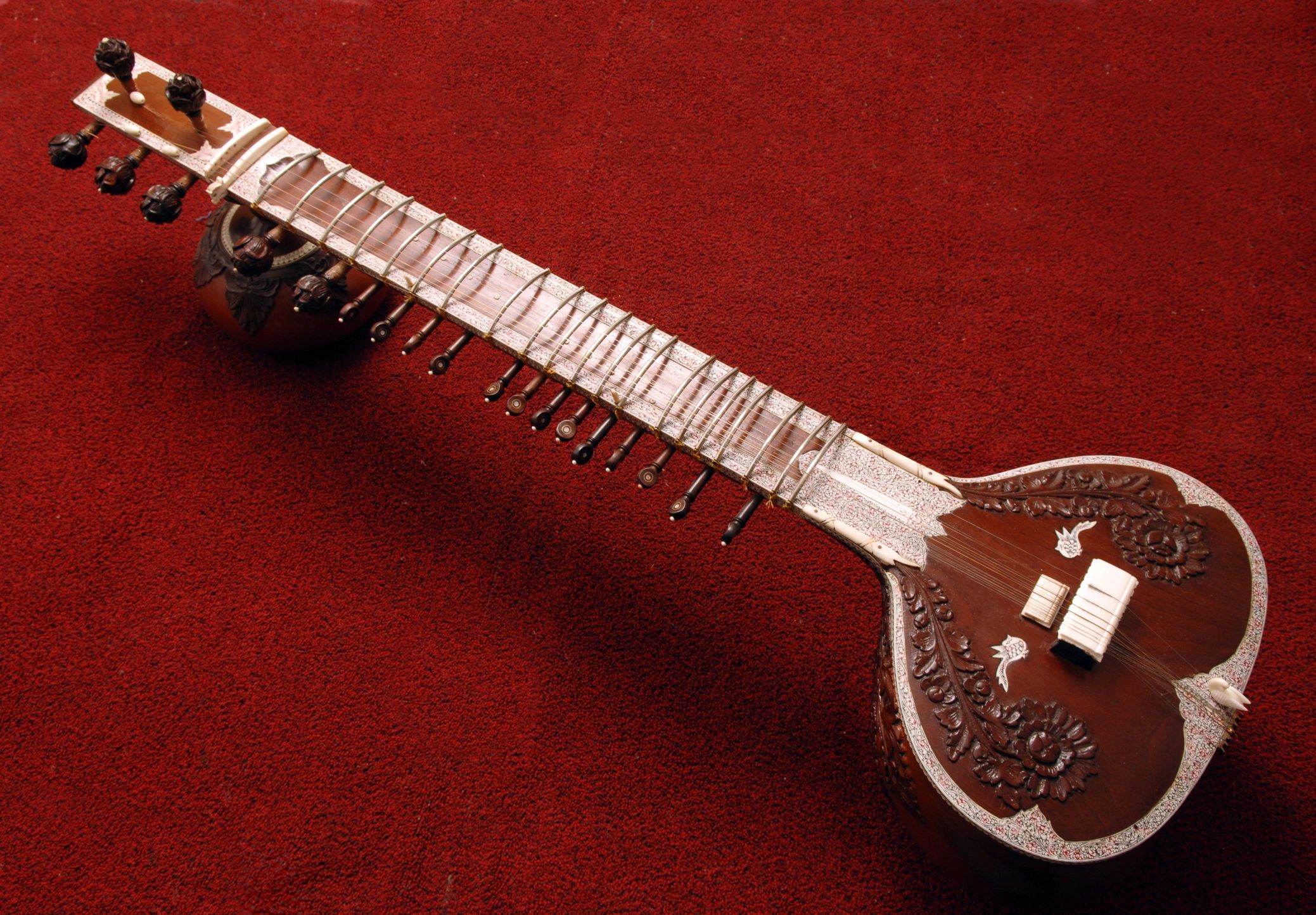 Close-up of a traditional sitar on a red carpet.