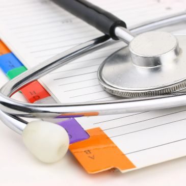 Stethoscope on a medical file with color-coded tabs.